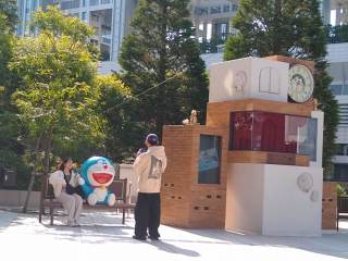 Doraemon A little park for Doraemon, including a bench where a guy is taking a girl's picture with a lifesize Doraemon figure