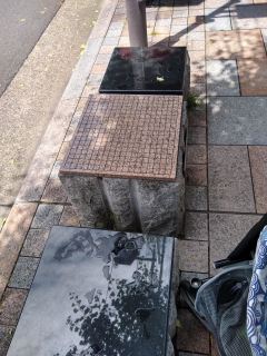 Go board A stone Go board, up on a stone table on a sidewalk. Two square stone seats are on the far side and the near side of the board.