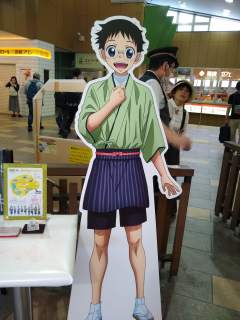Possibly A Train Station In Disguise A cardboard cut-out standee of a young boy in a traditional Japanese outfit at a train station